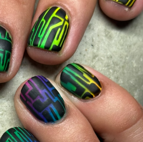 Close-up of short natural nails featuring a matte black base with colourful geometric linework in green, yellow, blue and purple.