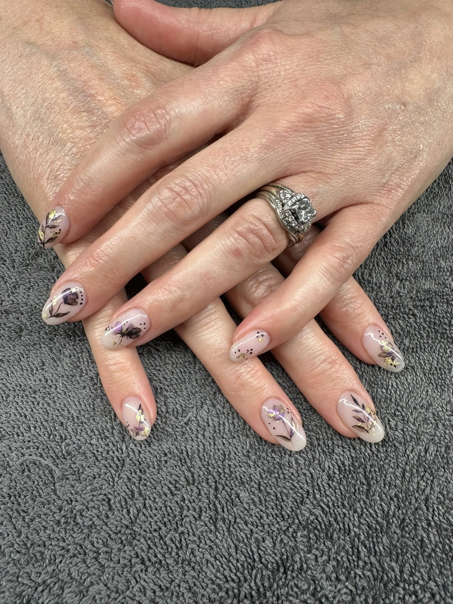 Delicate floral nail art with purple, black and gold details on a soft pink base, created by Roses Kustom Worx in Taupō.