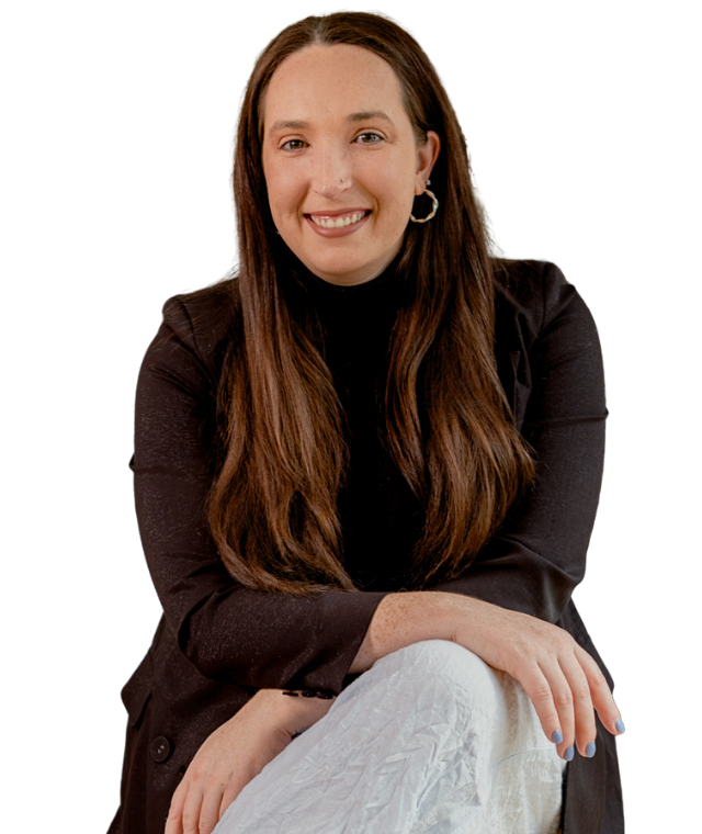 A woman with long brown hair, wearing a black blazer and hoop earrings, smiling and sitting with one arm resting on her knee.