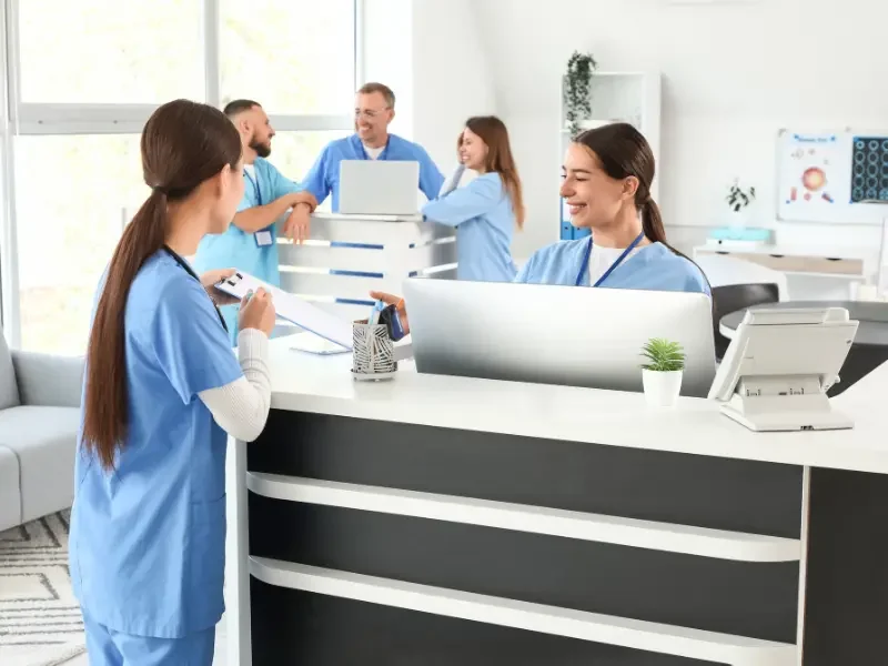 Natural health center business team collaborates at a modern front desk in a bright medical facility