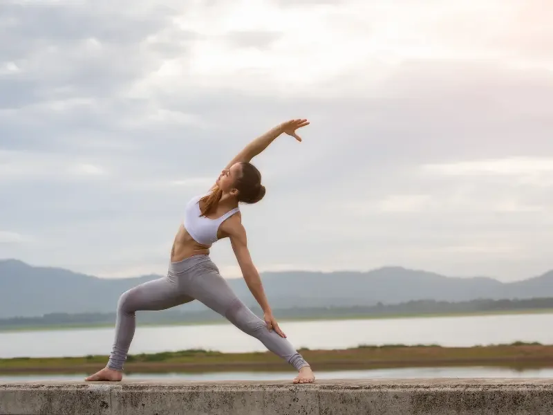Holistic healthcare practice depicted by a woman doing yoga outdoors for physical and mental balance