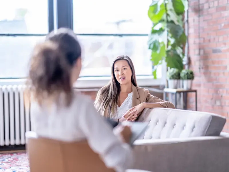 Therapy session between two women in a modern office focuses on mental health support and personal growth