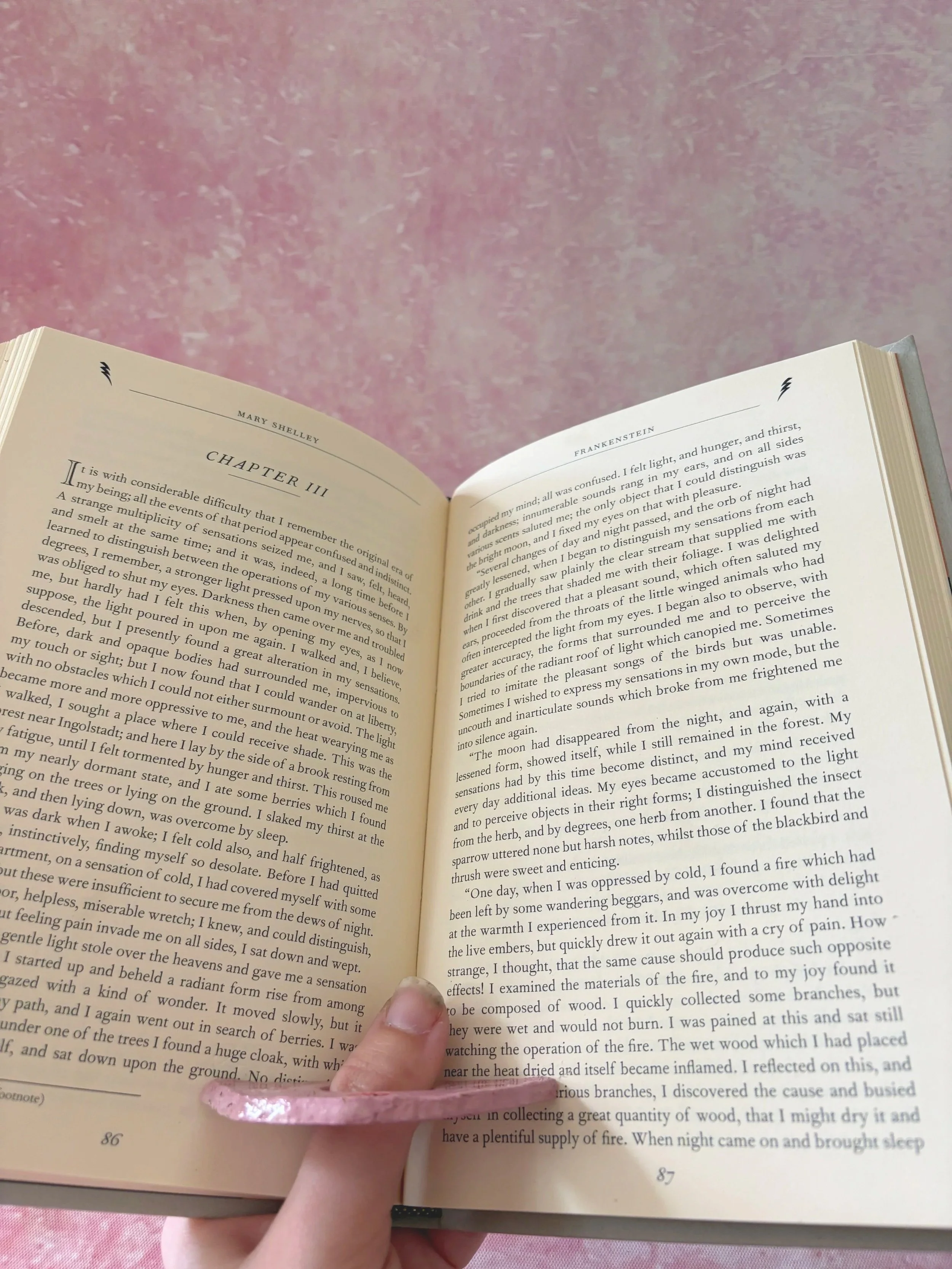 Pink bow patterned page holder in use, holding a book open.