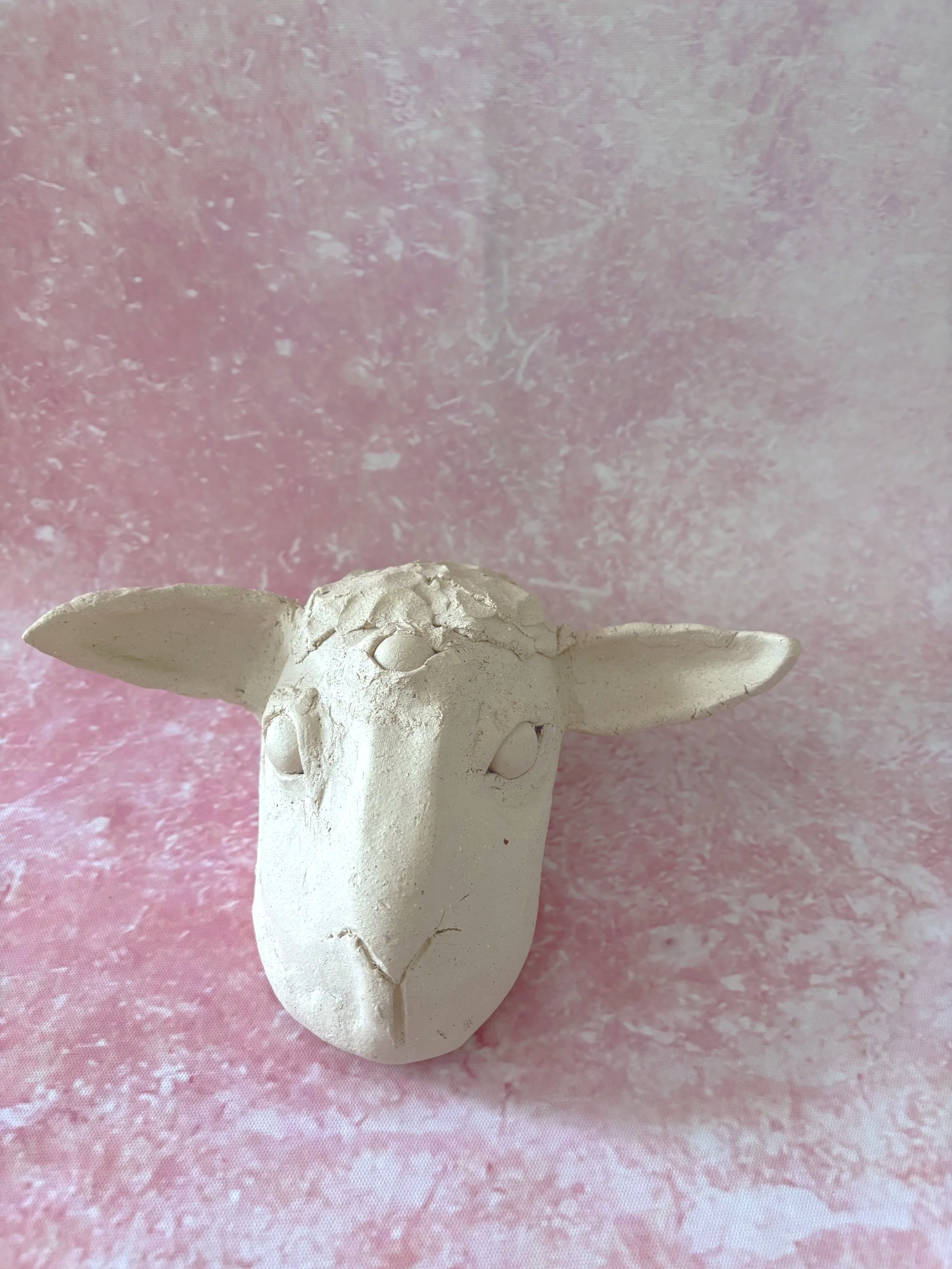 A white, unglazed, ceramic three eyed lamb.