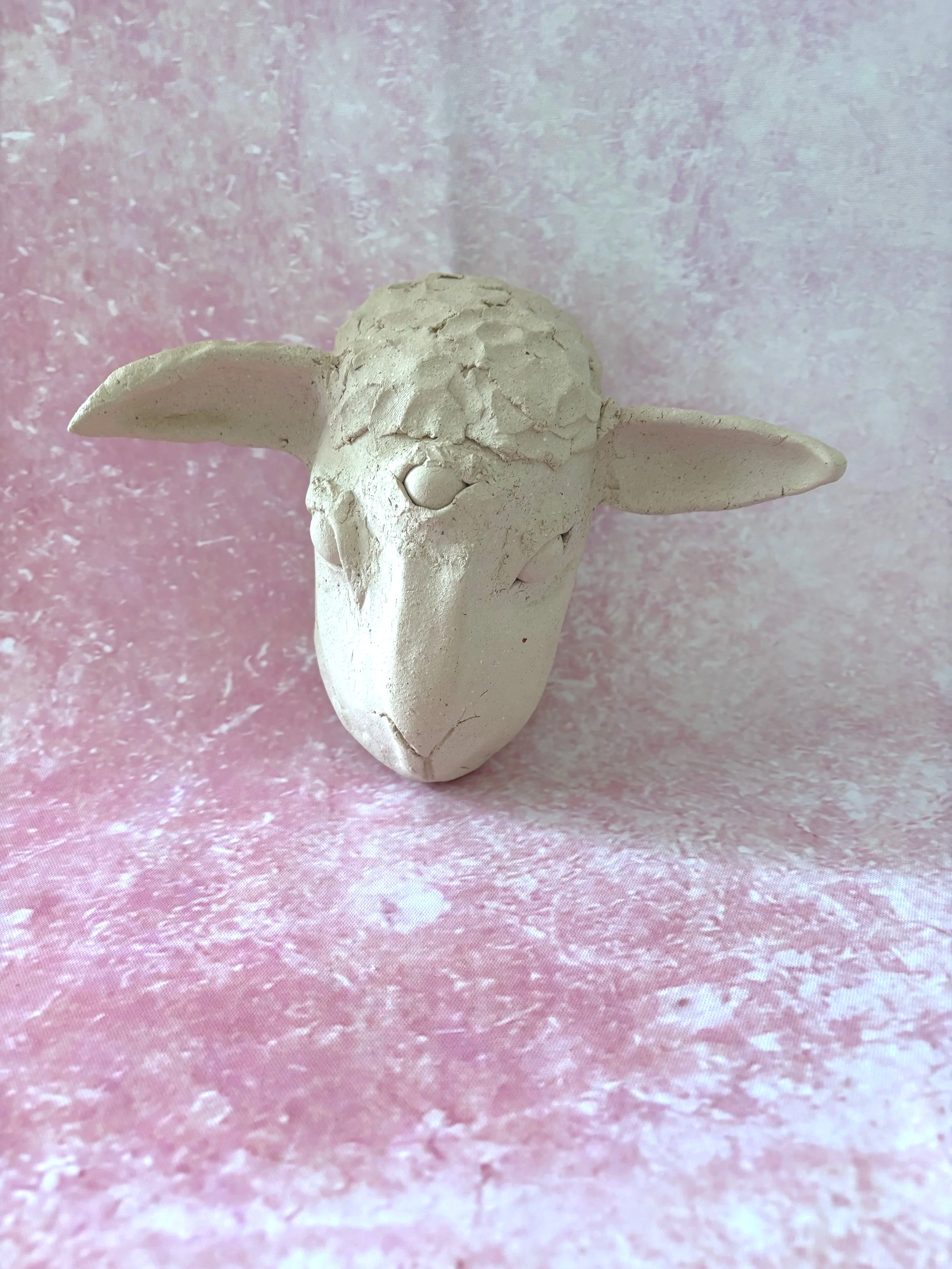 A white, unglazed, ceramic three eyed lamb.