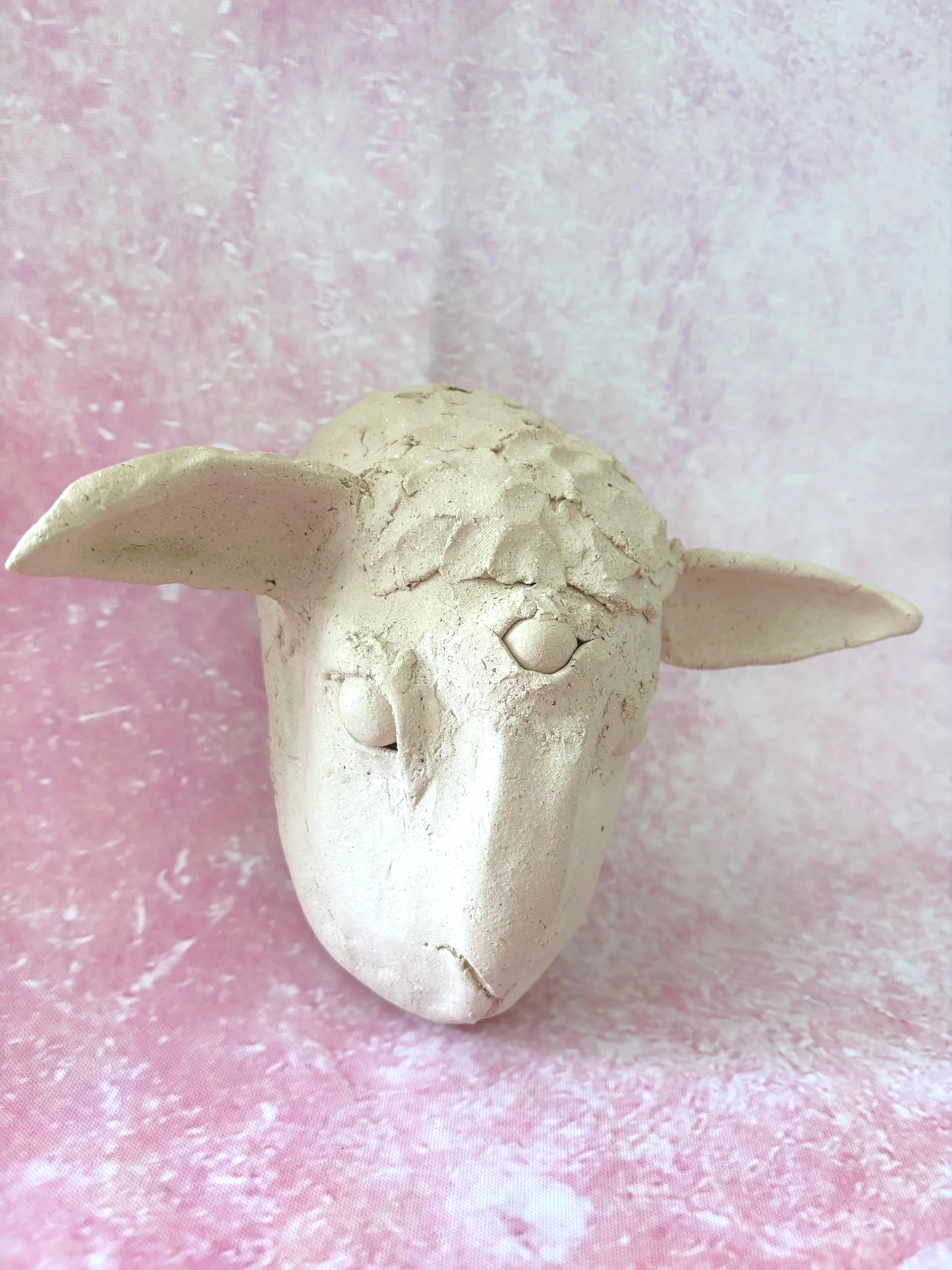 A white, unglazed, ceramic three eyed lamb.