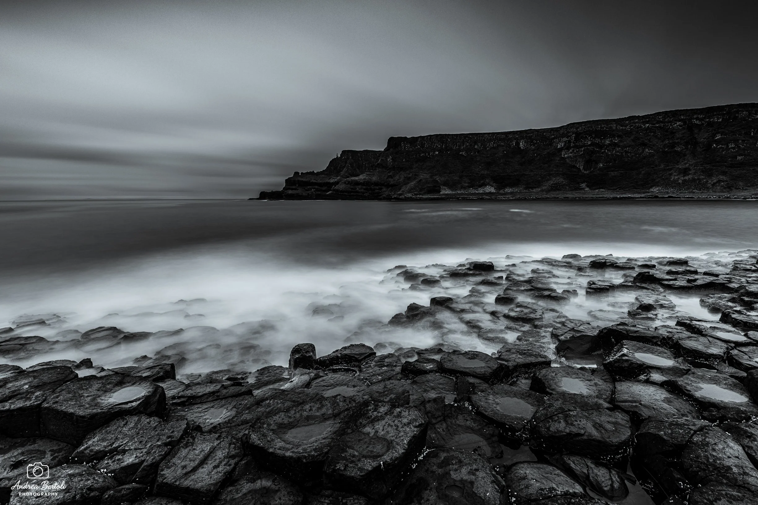Il Giant's Causeway in un paesaggio costiero con nuvole scure.