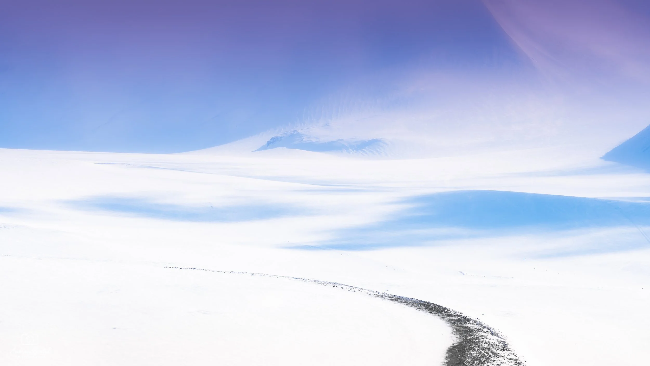 Paesaggio innevato con vasto campo di neve e montagne in lontananza sotto un cielo azzurro alle Svalbard.