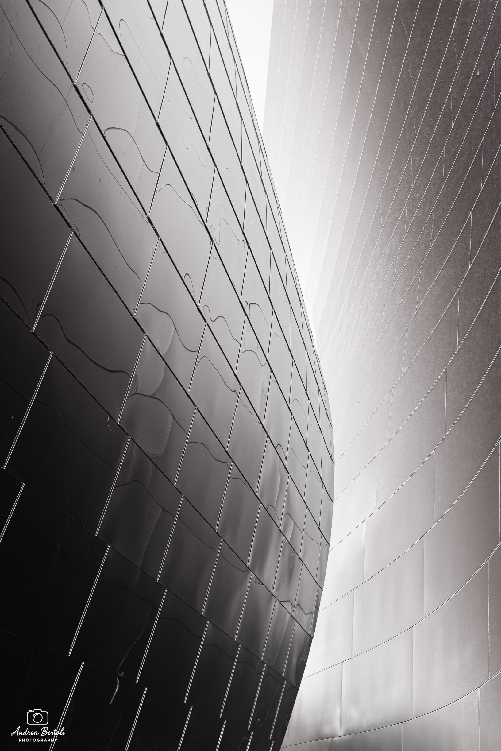 Immagine del Walt Disney Concert Hall con pareti di vetro lucide e linee rette, ripresa da una angolazione obliqua.