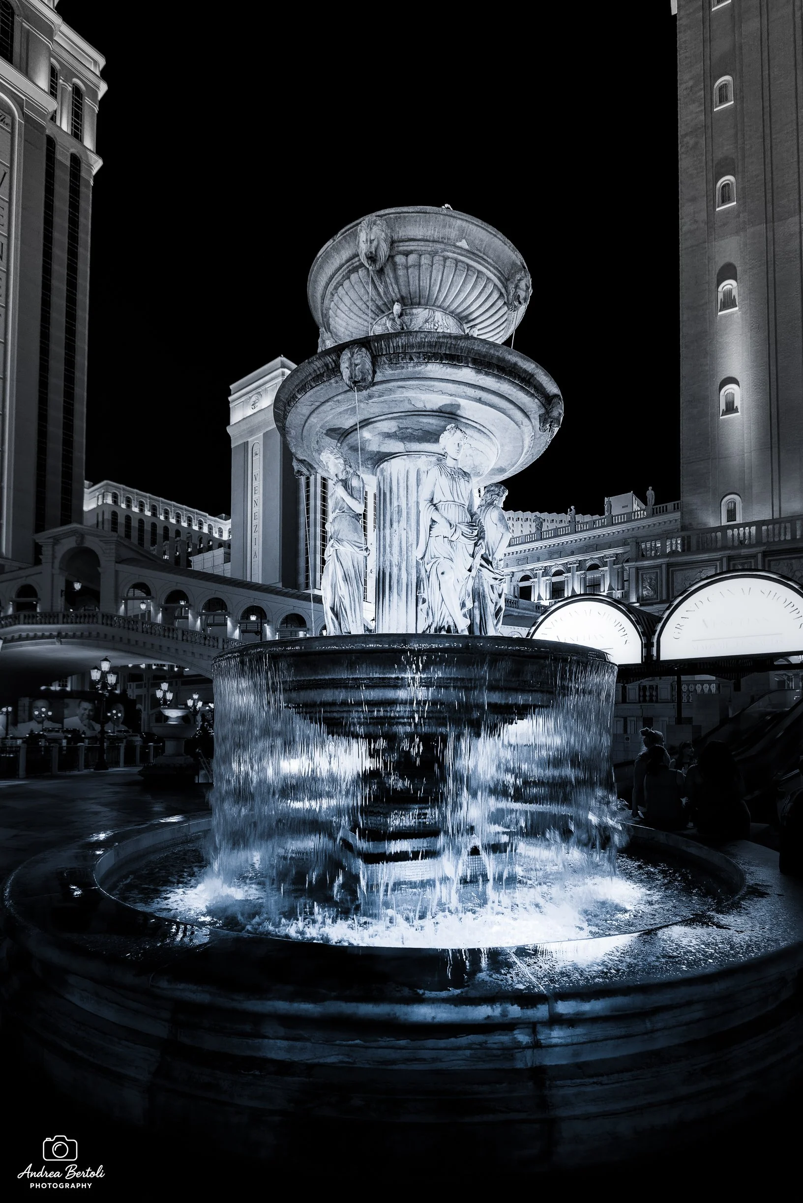 Fontana decorativa a Las Vegas con statue di donne in stile classico, illuminata di notte, con edifici moderni sullo sfondo.