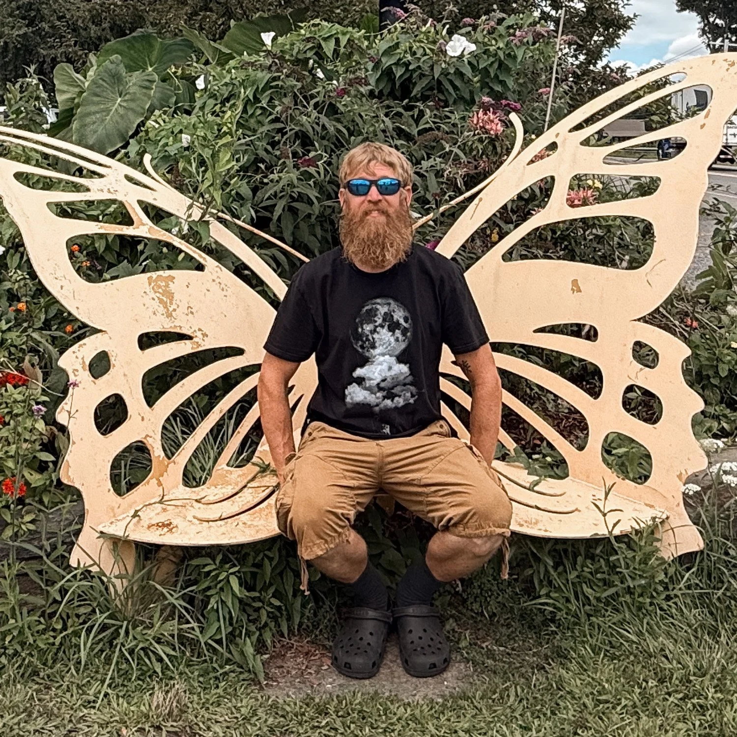 Charlie, part of the We Love Land team sitting on a butterfly bench.