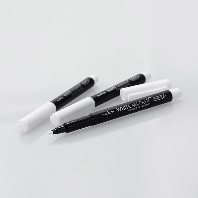 Four black and white whiteboard markers with caps, laid out on a reflective white surface.