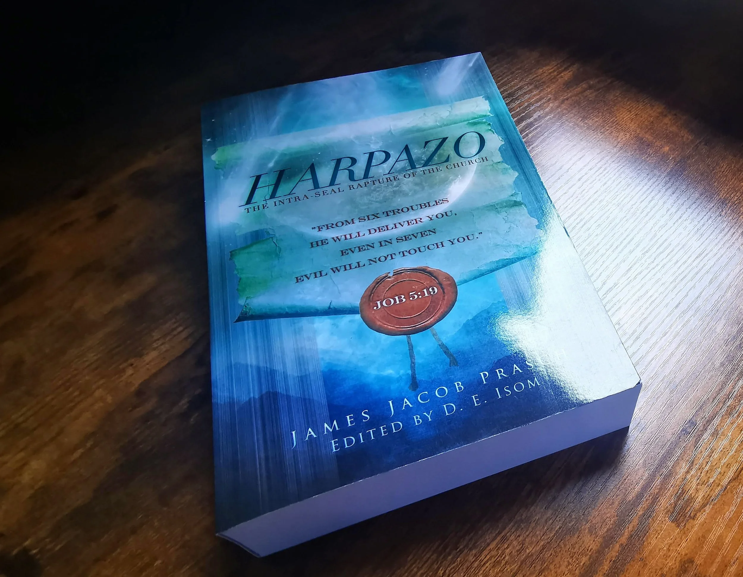Close-up of a book titled 'HARPZO: The intra-seal rapture of the church' with a Bible quote from Job 5:19 on a wooden surface.