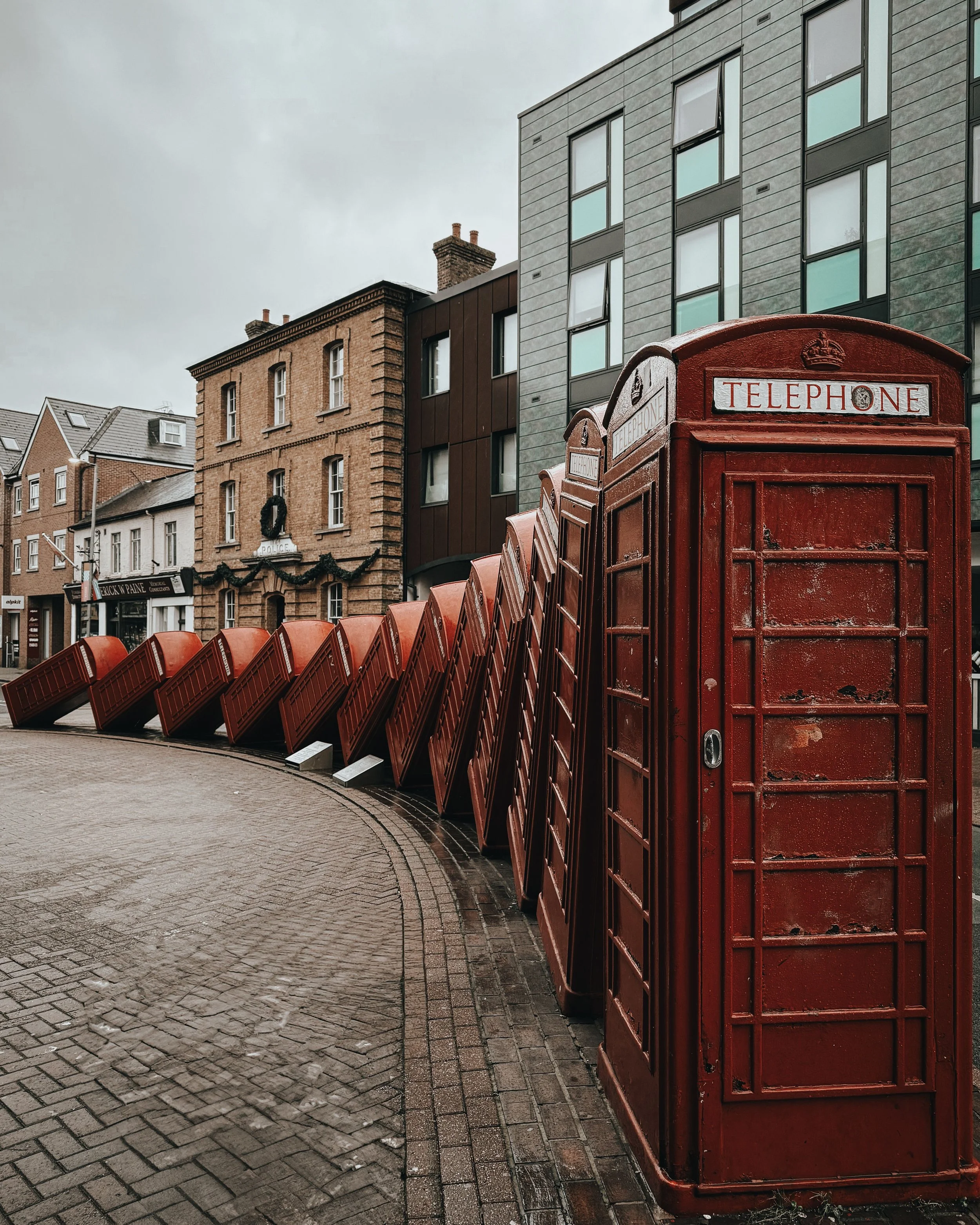 "Out of Order" - iconic artwork of curved line of falling down red telephone boxes In Kingston Upon Thames, UK
