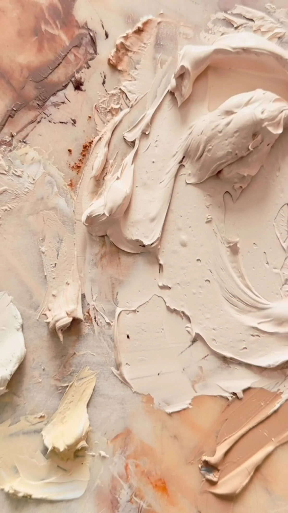Trazos y texturas de pintura en colores beige, blanco y marrón en una superficie con rasguños y manchas.