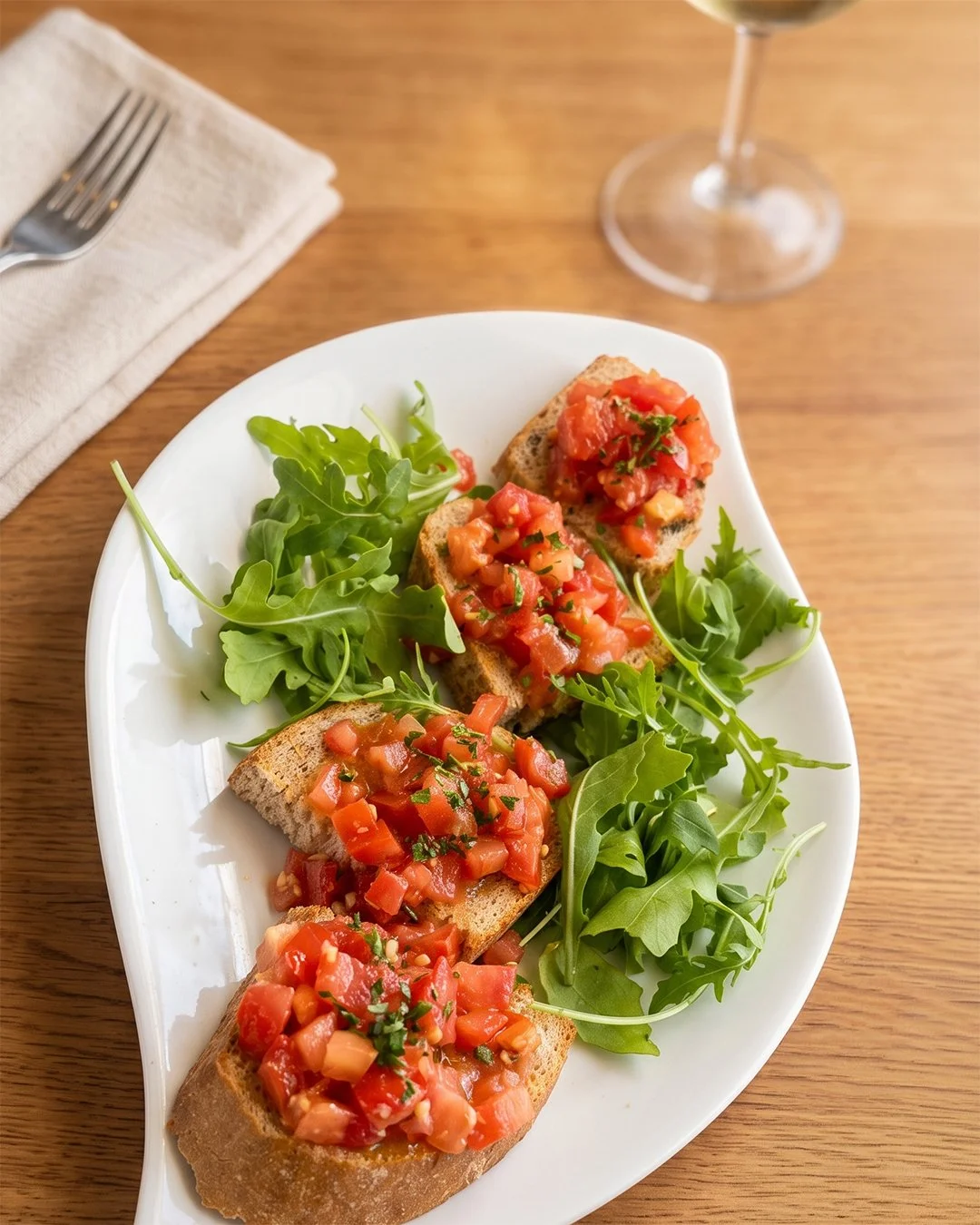 Tartines avec tomates et herbes, accompagnées de roquette sur une assiette blanche.