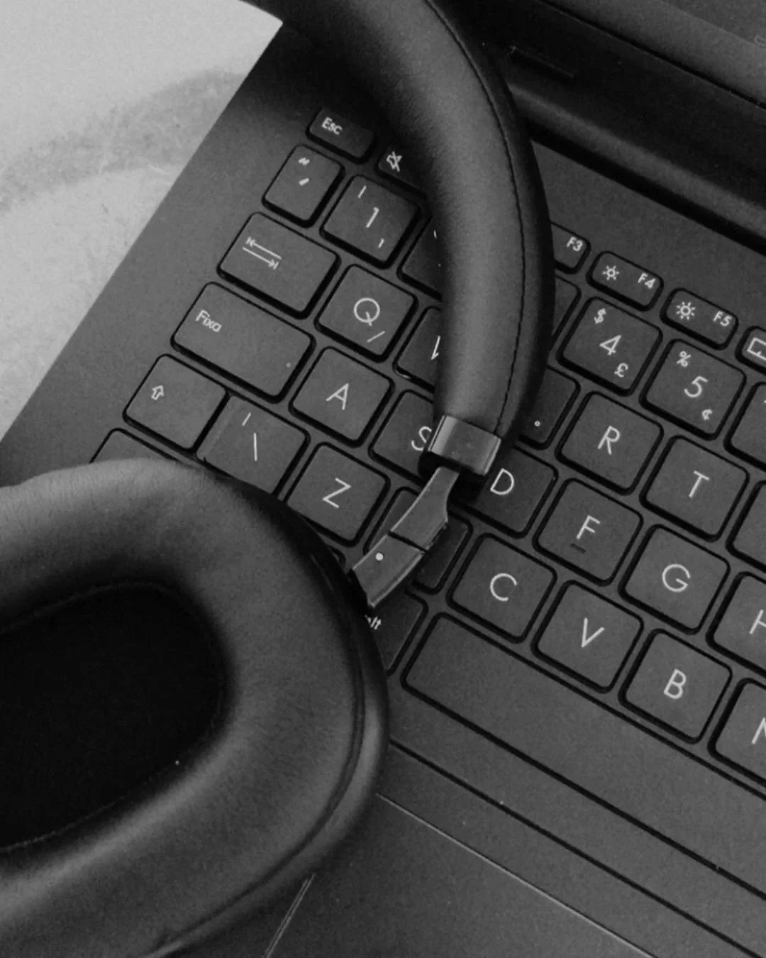 Black wireless headphones resting on a computer keyboard.