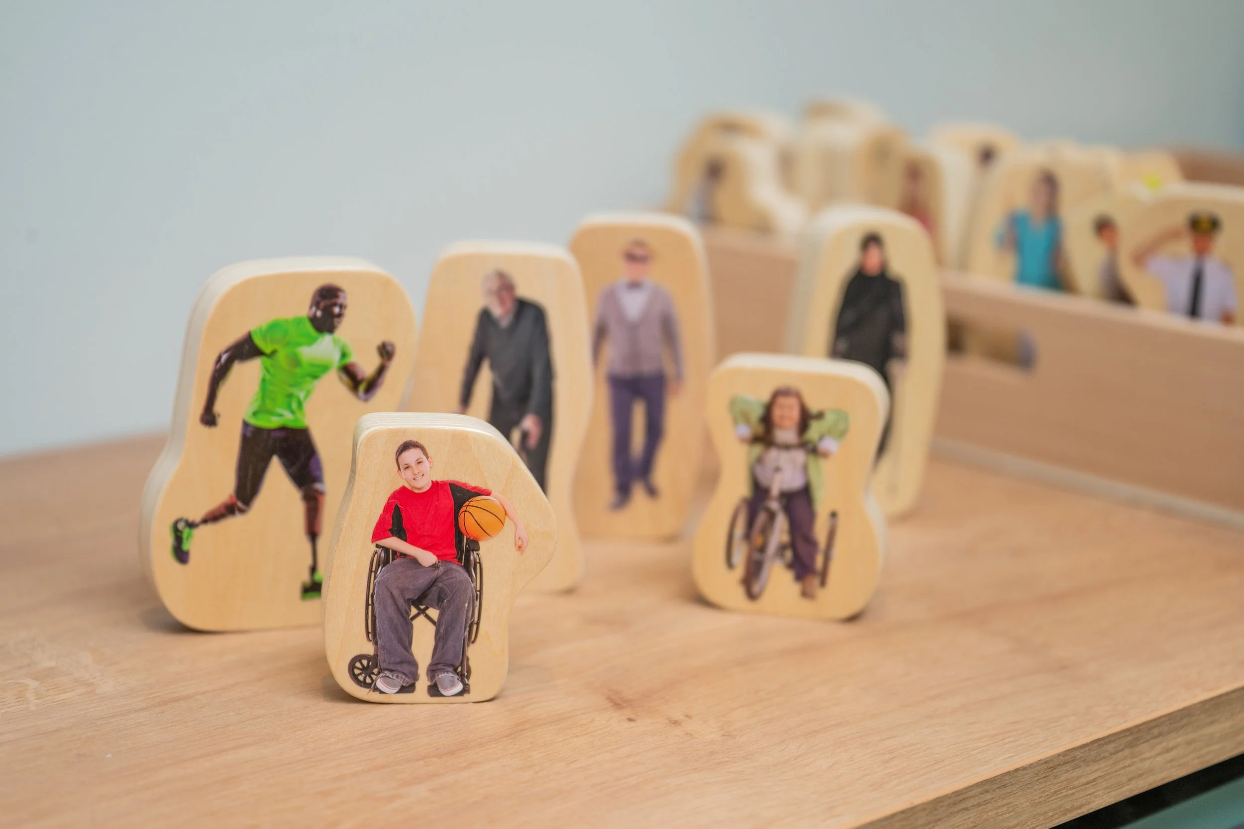 Wooden figurines with printed photos of people on a wooden surface.