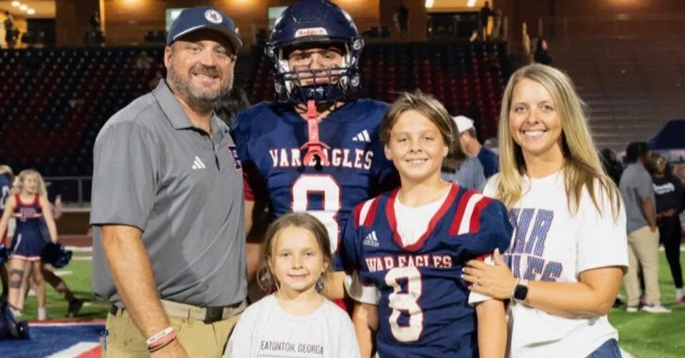Family and football players on a field celebrating after a game.
