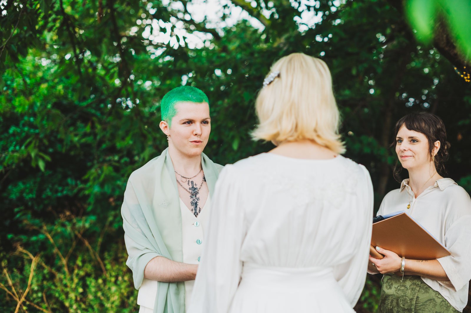 - [ ] Hannah conducts he wedding of a non-binary person with green hair and a woman with blonde hair wearing a white wedding dress