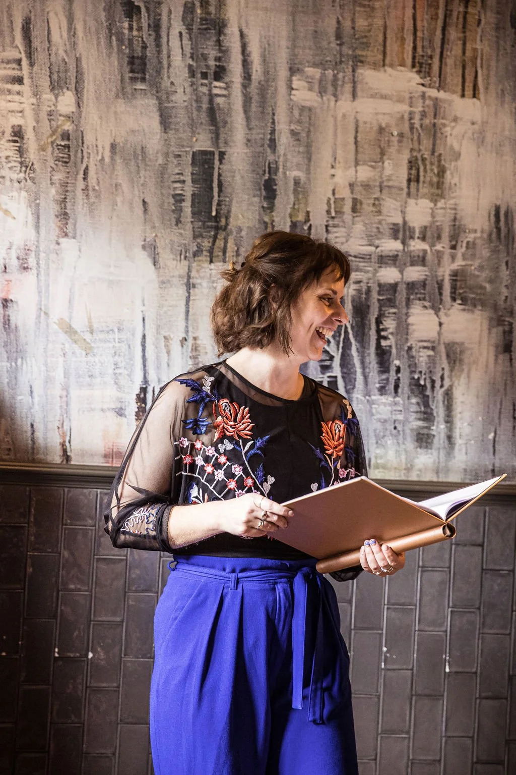 Hannah is laughing as she reads out loud from her script at a wedding