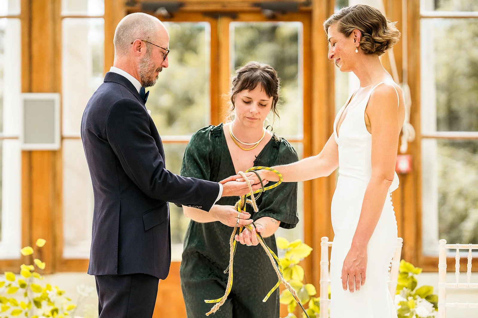 Hannah is performing a handfasting for a cis-het couple, and they are all looking peaceful and emotional