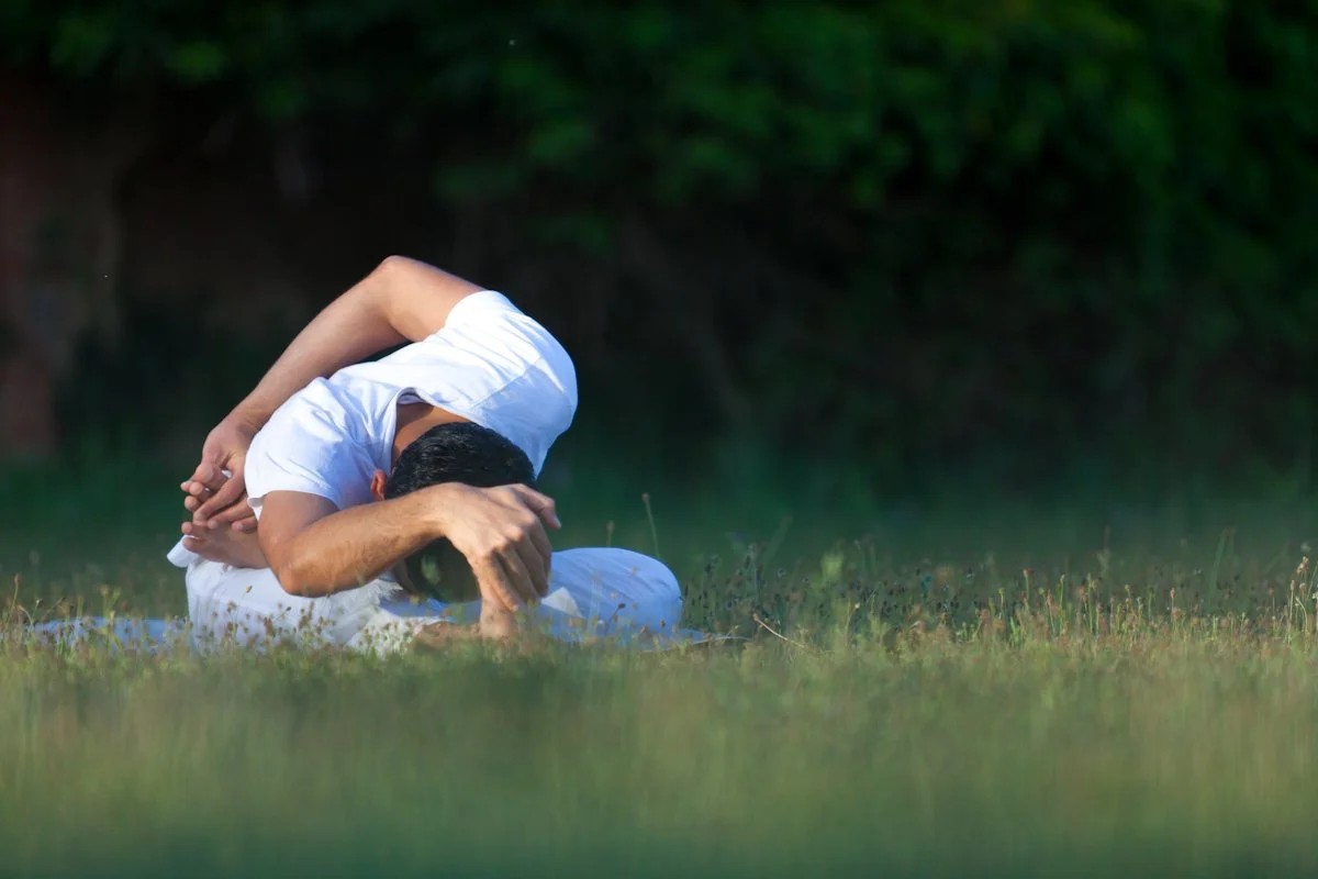 Persona practicando yoga en el pasto al aire libre