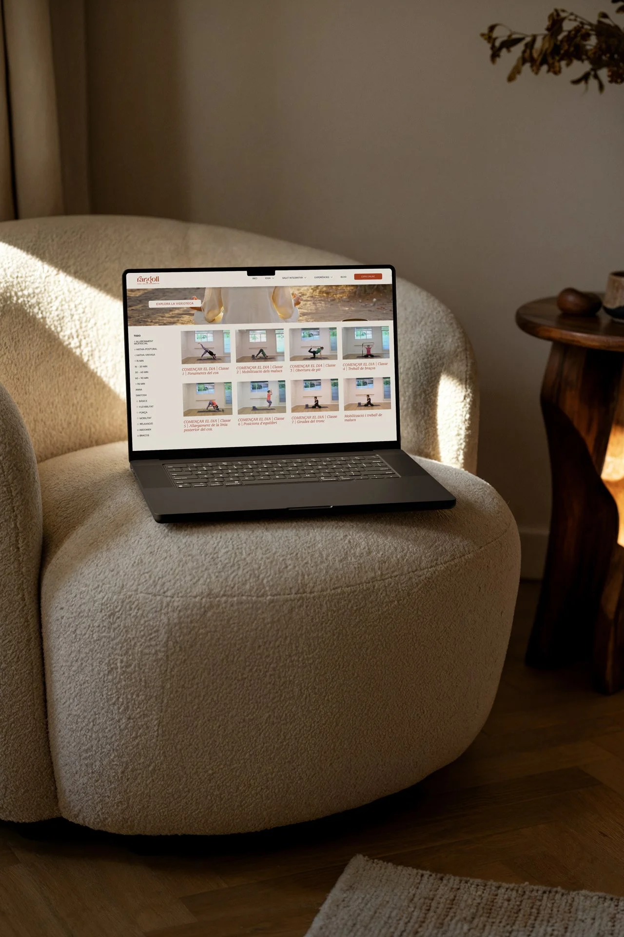 Portátil con página web sobre yoga y ejercicios en un sillón en una sala de estar