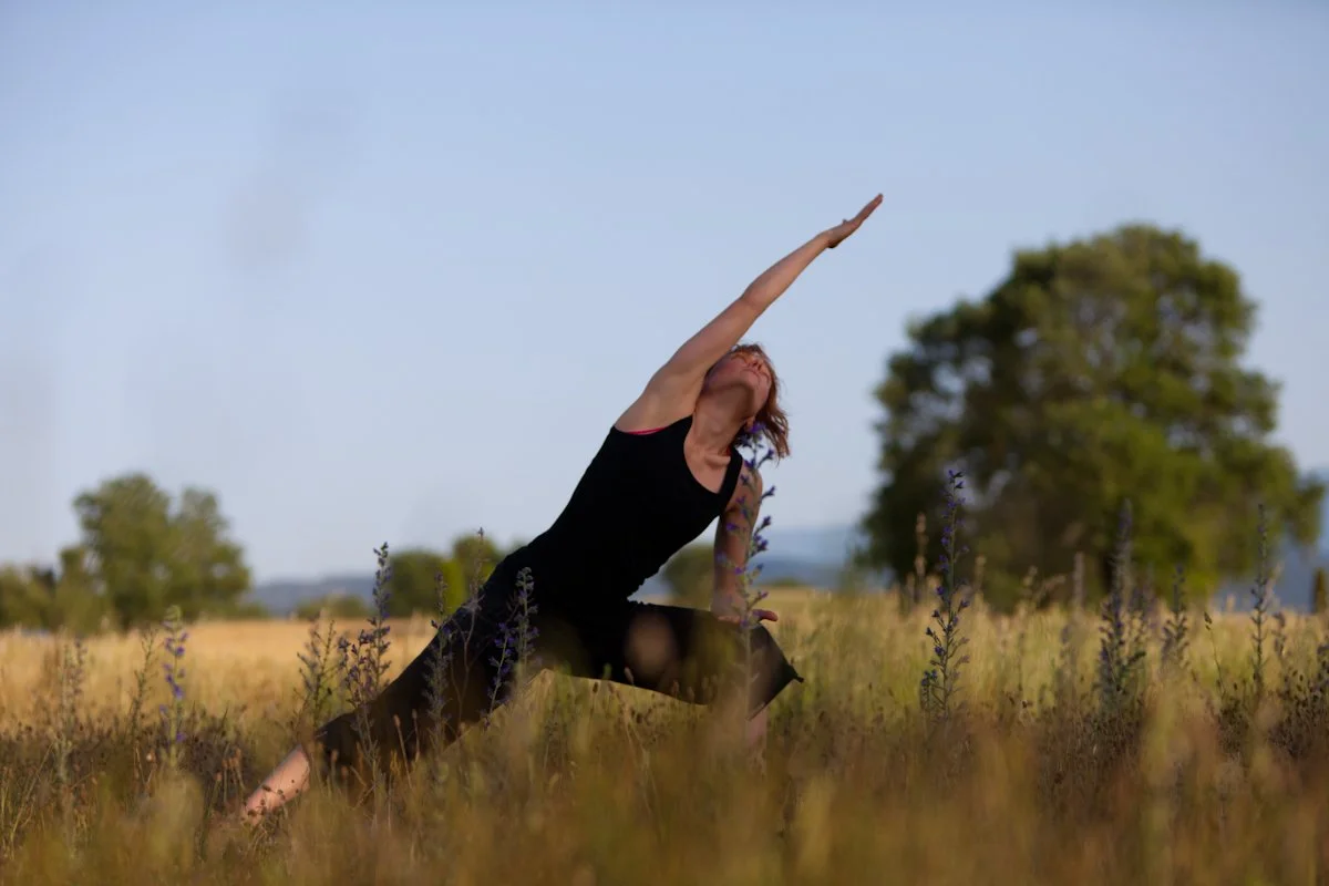 Mujer realizando yoga en un campo abierto durante el día
