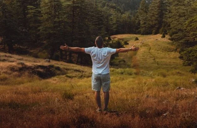 A man standing outside with arms outstretched