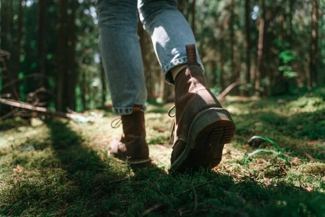 A closeup of a pair of hiking boots walking in the woods