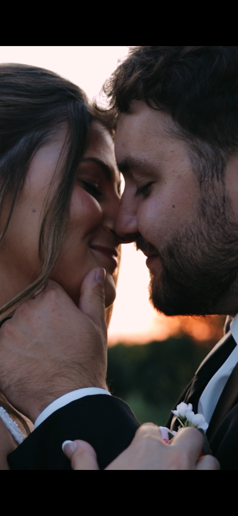 Close-up of a couple with foreheads touching, gently smiling, during sunset, with romantic and intimate mood.