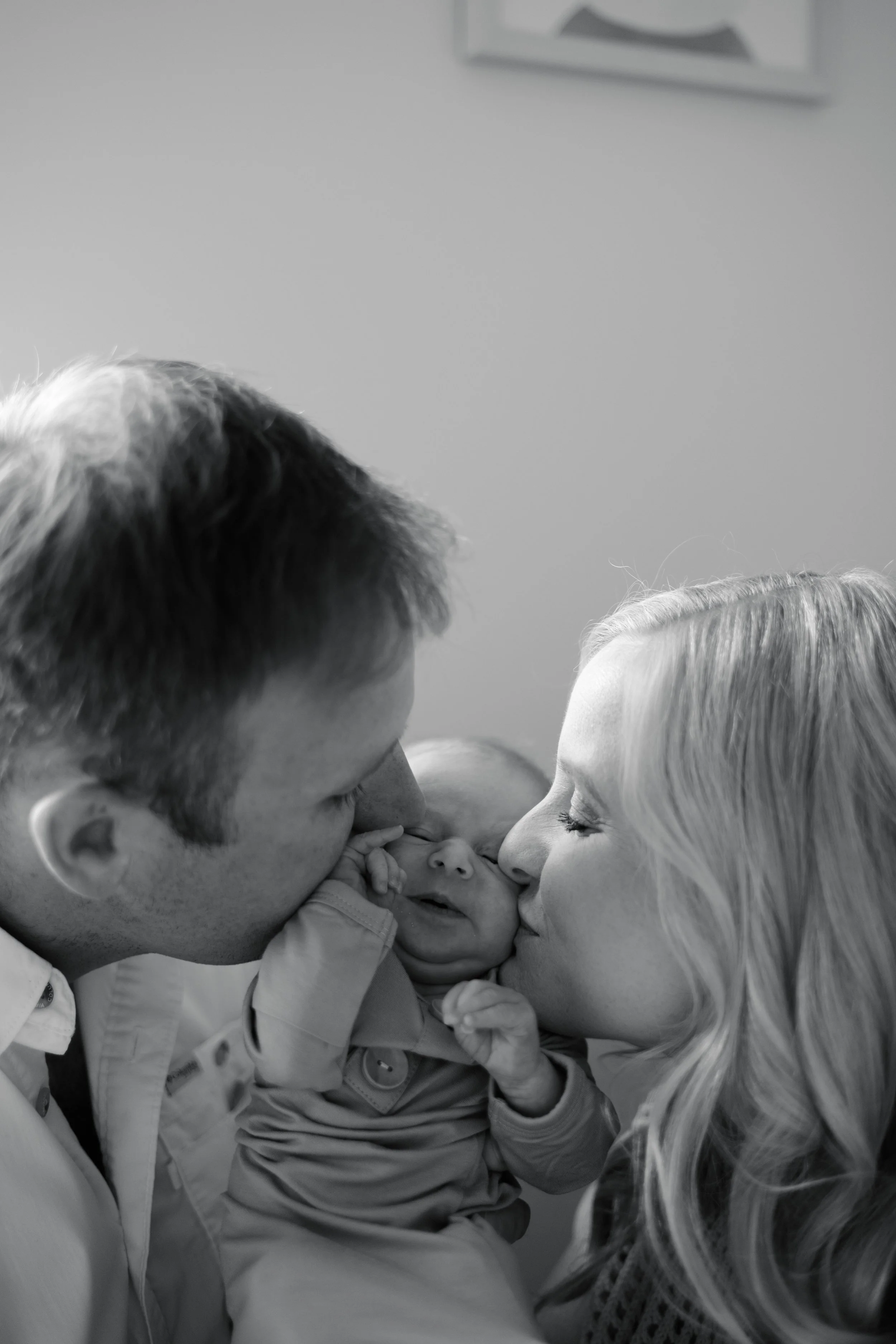 A family of four, including a father, mother, and two babies, sharing a close, affectionate moment.