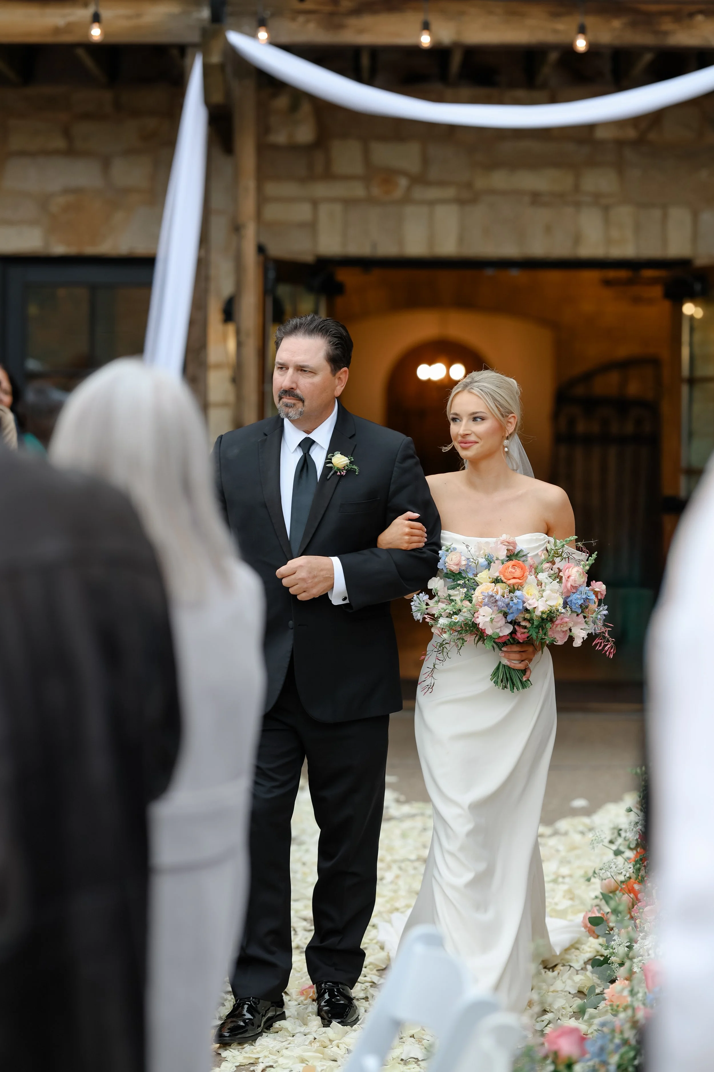 A bride walking down the aisle with her father at a wedding ceremony.