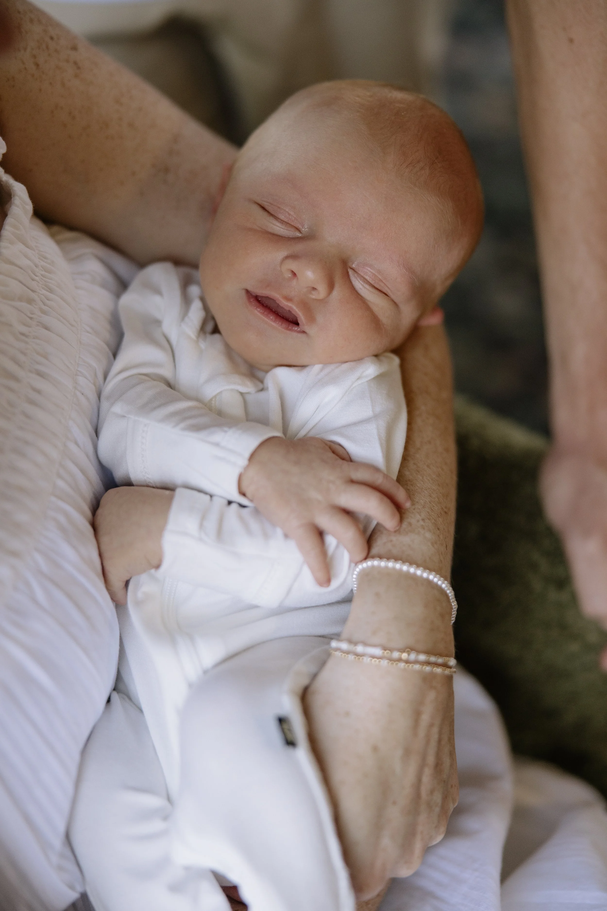 Close-up of a newborn baby peacefully sleeping, being cradled in an adult person's arms.