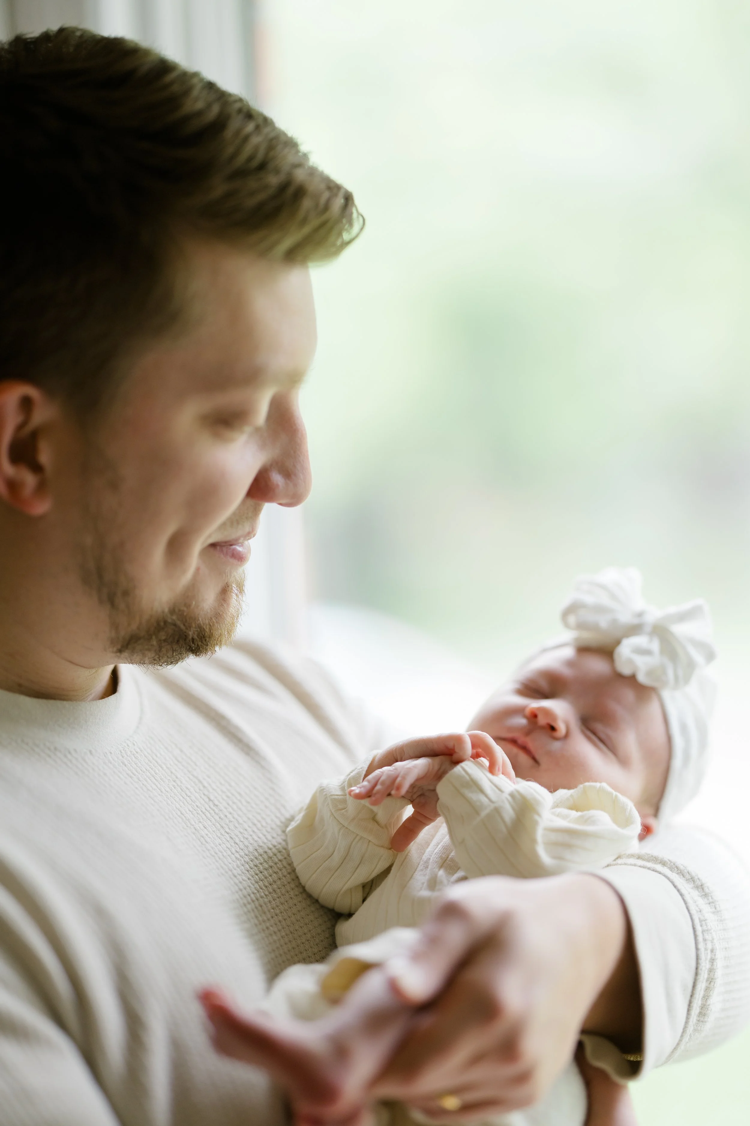 A man holding a sleeping newborn baby in his arms.