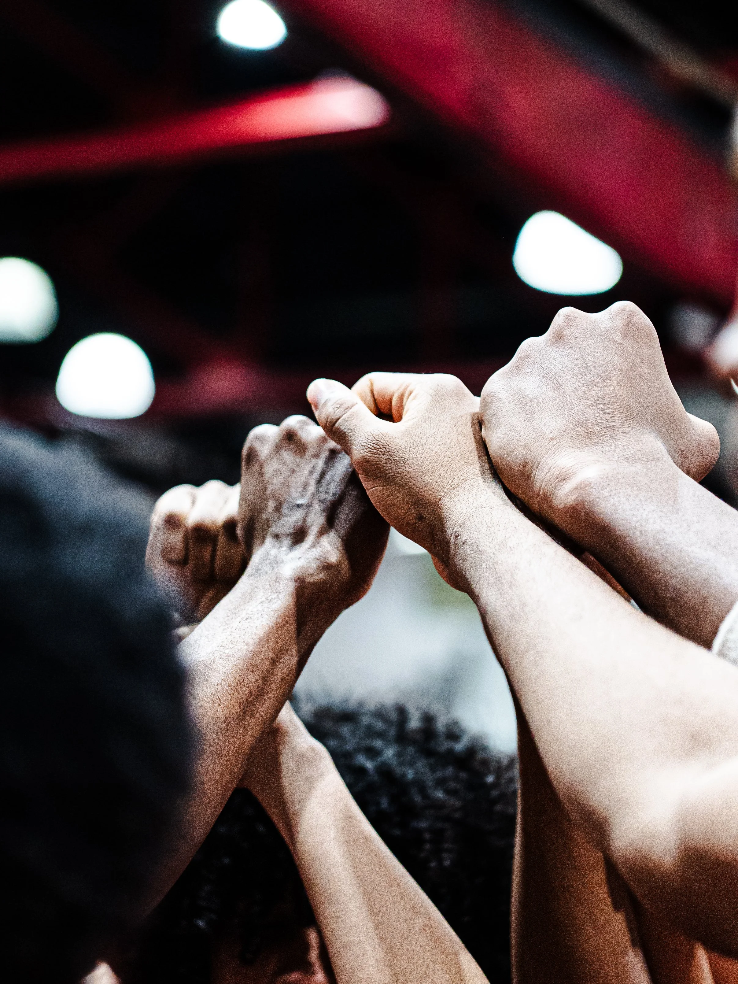 A group of diverse hands and arms holding each other in a circle, symbolizing unity and teamwork.