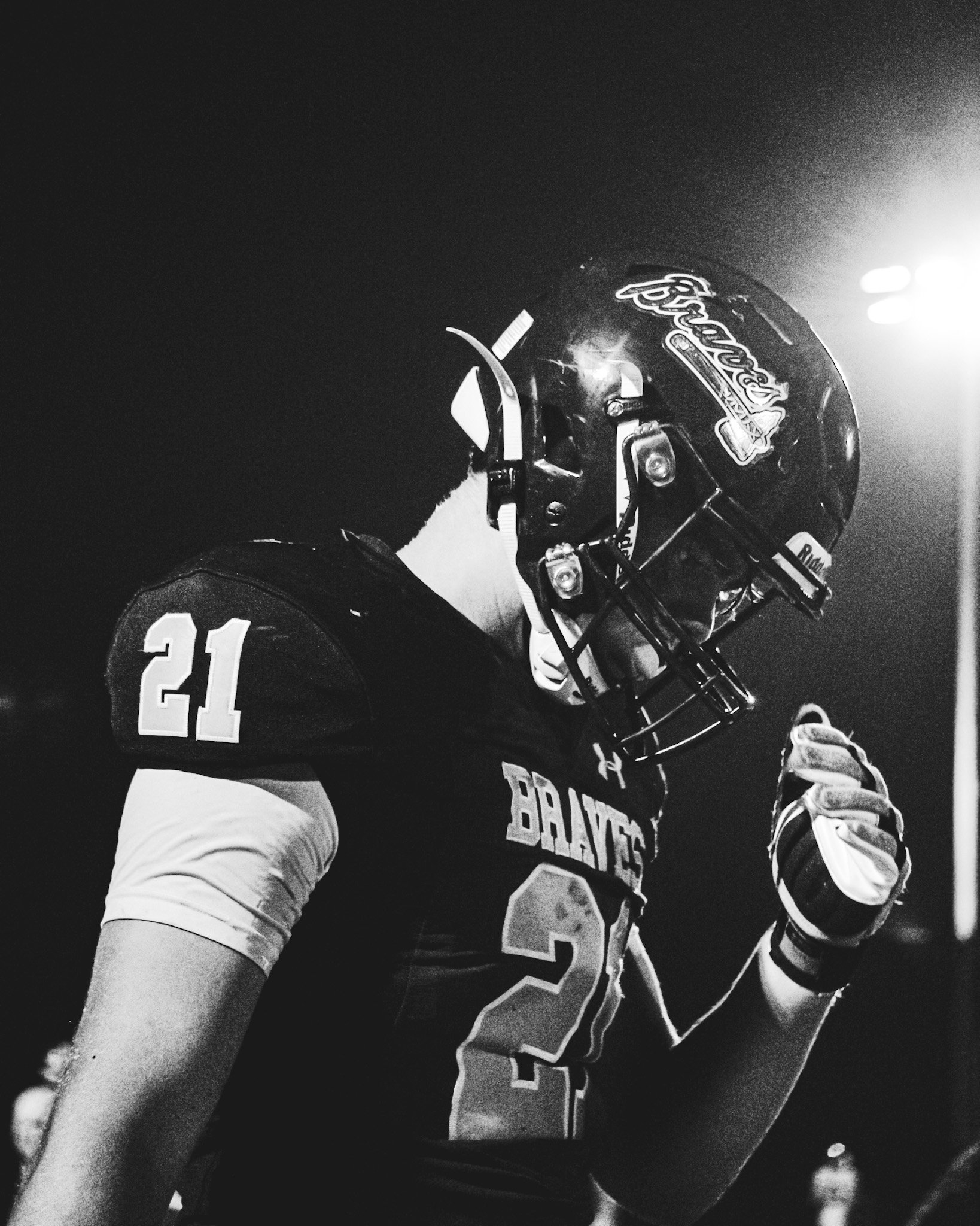 A football player wearing a jersey with the number 21 and a helmet, partially visible on a dark background.