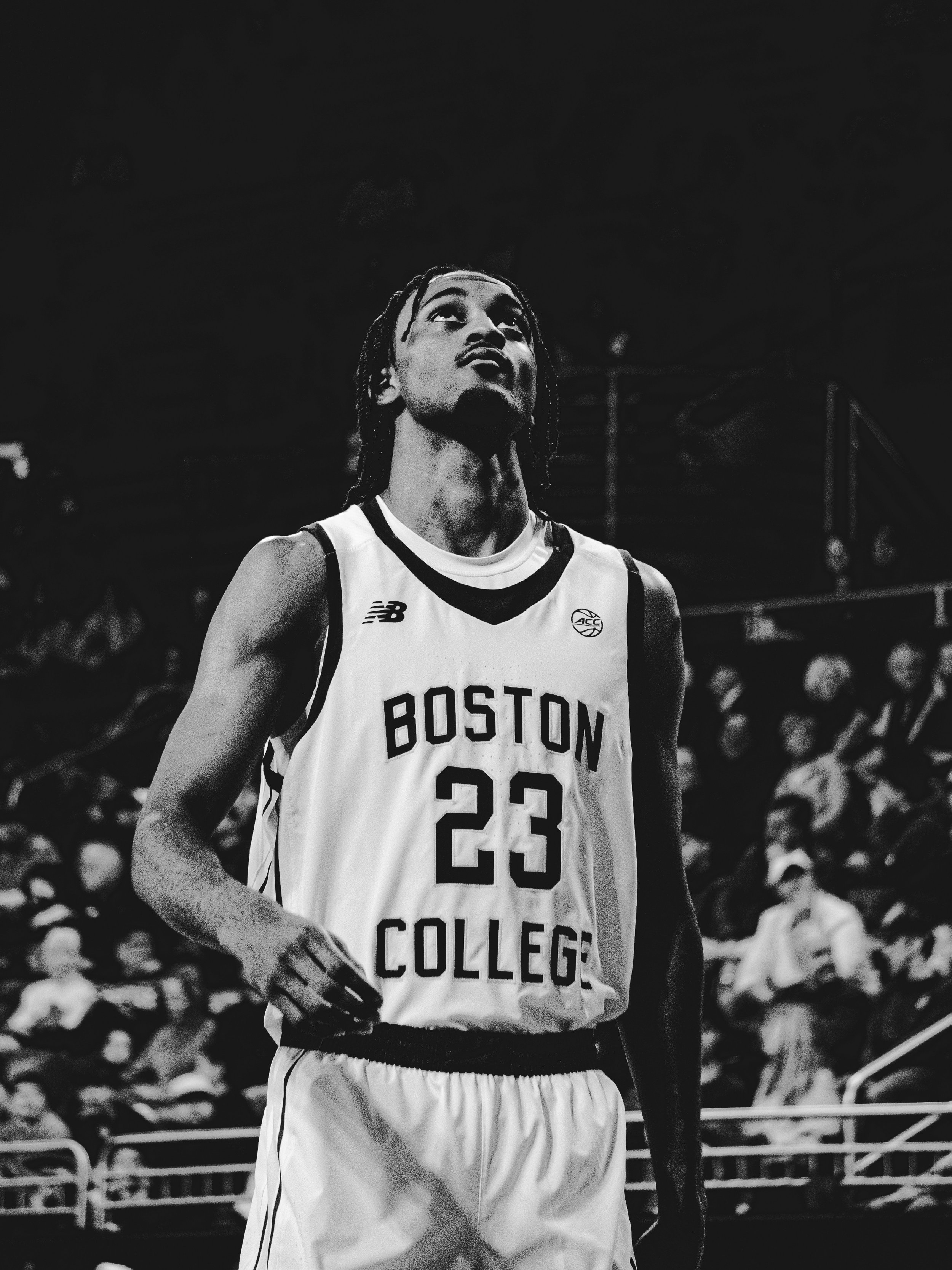 Black and white photo of a male basketball player in a Boston College jersey, looking up, with a crowd in the background.