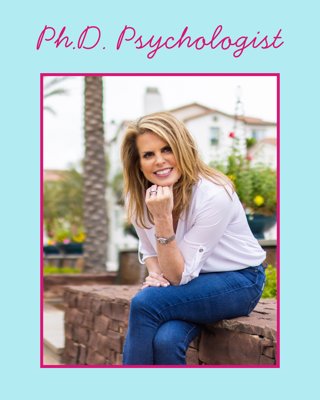 A woman sitting on a brick ledge outdoors, smiling and resting her chin on her hand, with a background of palm trees and houses.