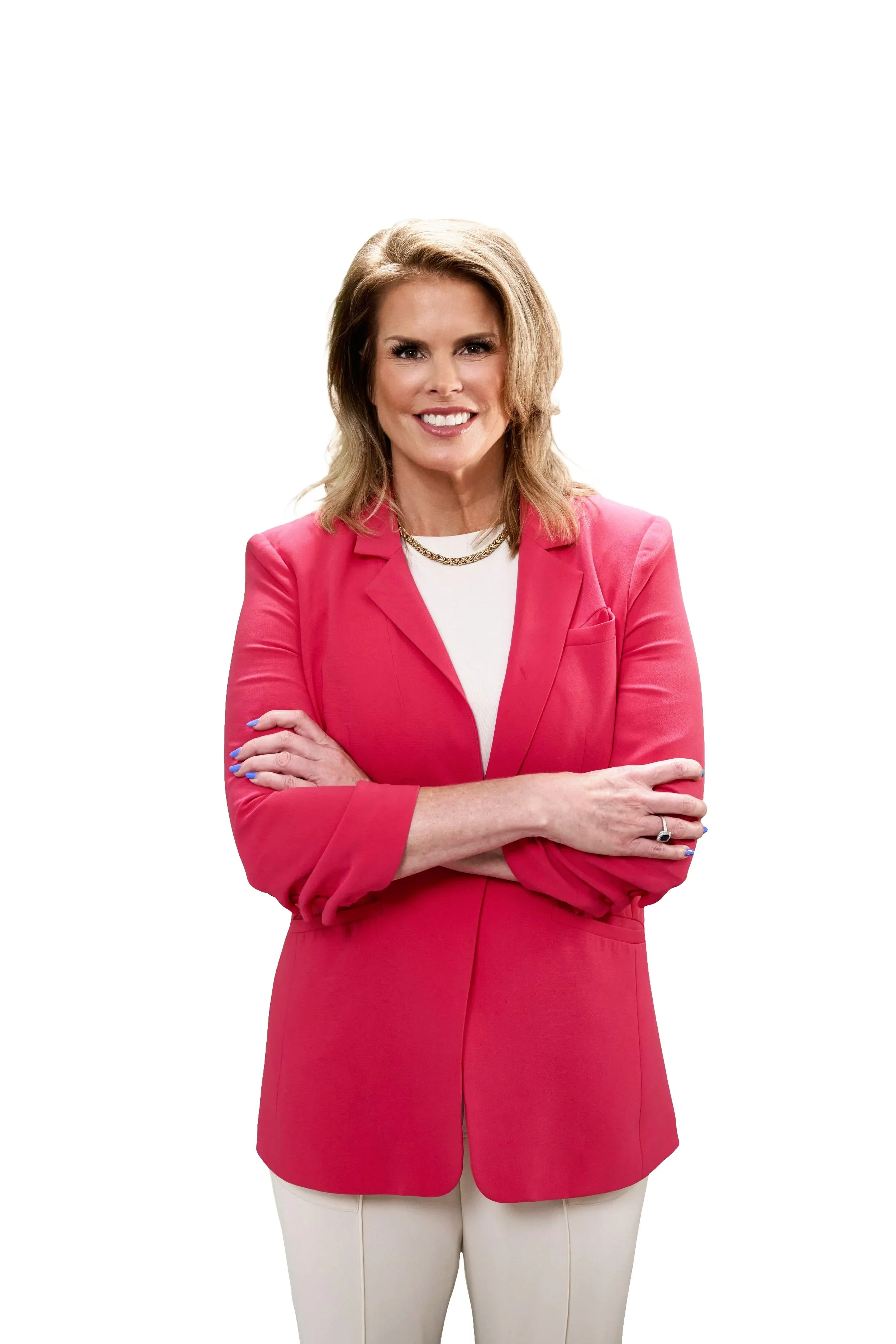 A woman with blonde hair, dressed in a pink blazer and white shirt, smiling with arms crossed, standing against a white background.