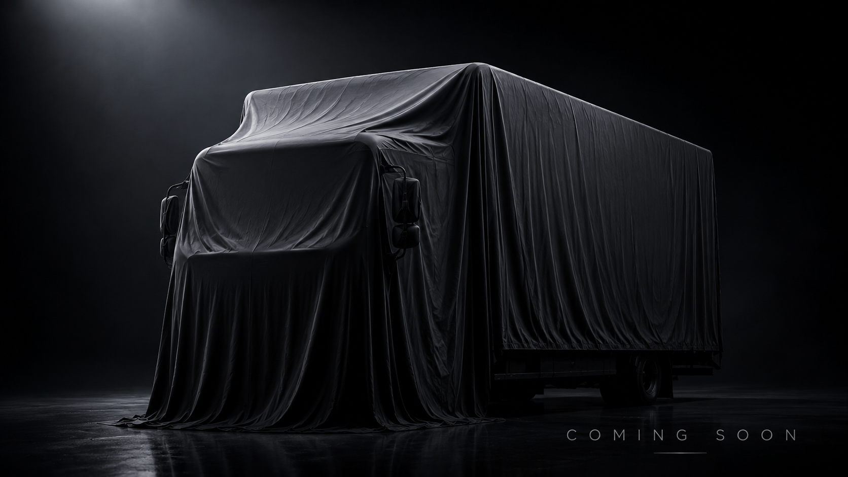 A dark, mysterious vehicle covered in black fabric, with the words 'Coming Soon' in the bottom right corner, suggesting an upcoming reveal.