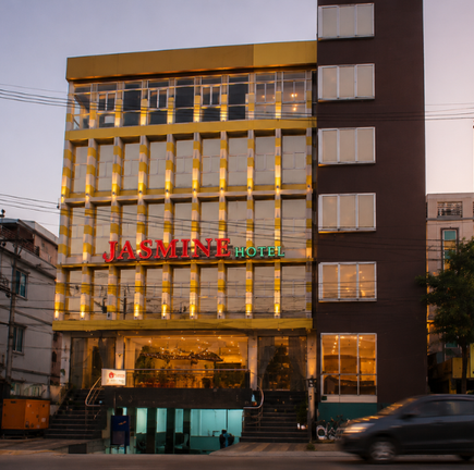 Exterior of Jasmine Hotel with illuminated gold and glass facade at dusk.