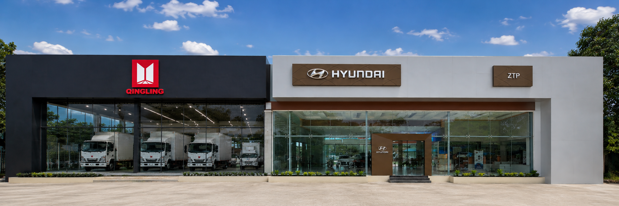 A modern car dealership with Hyundai and QingLing brands, featuring large glass windows displaying cars inside, a clear sky, and minimal landscaping.