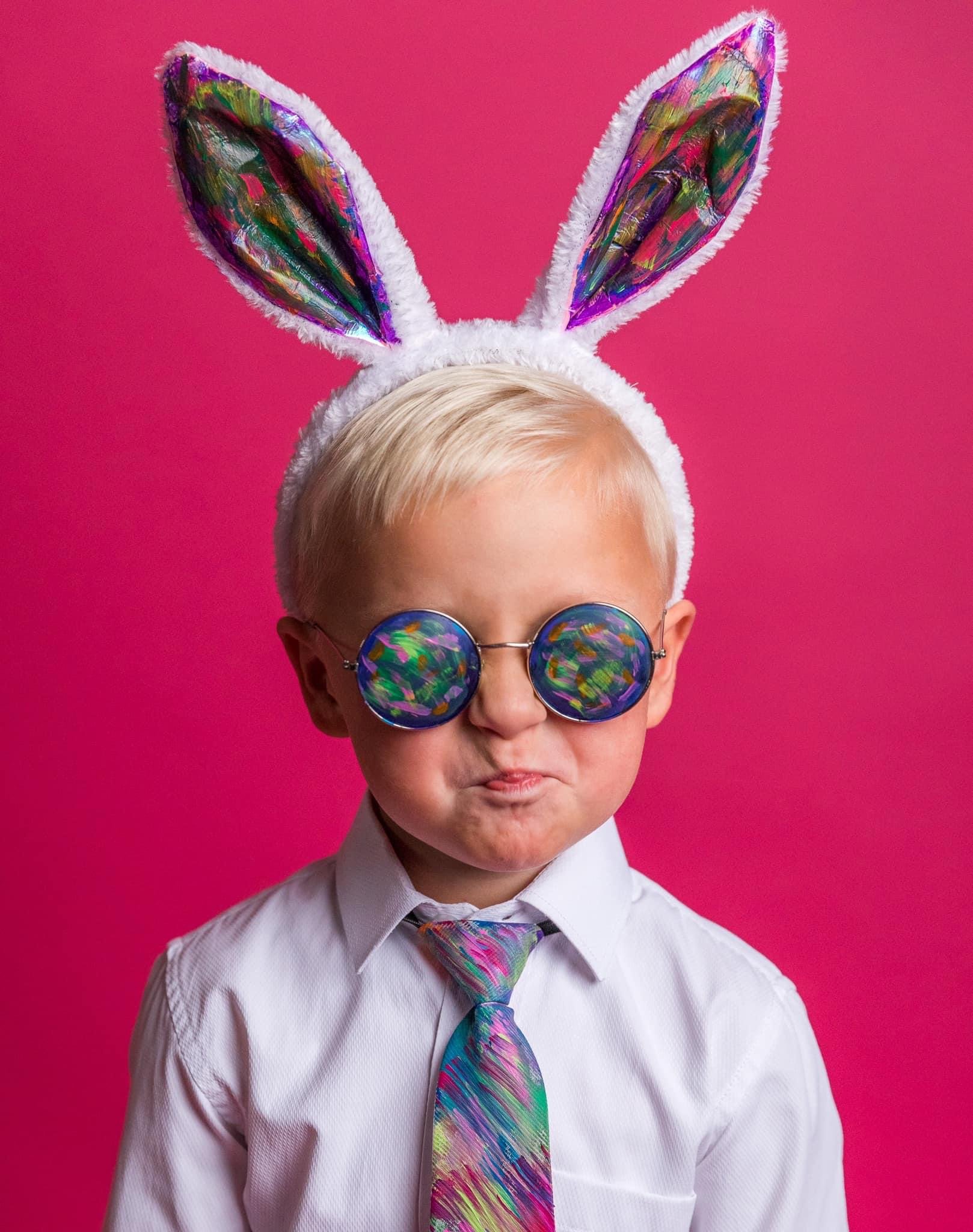 Person wearing bunny ears and glasses against a bright pink background.