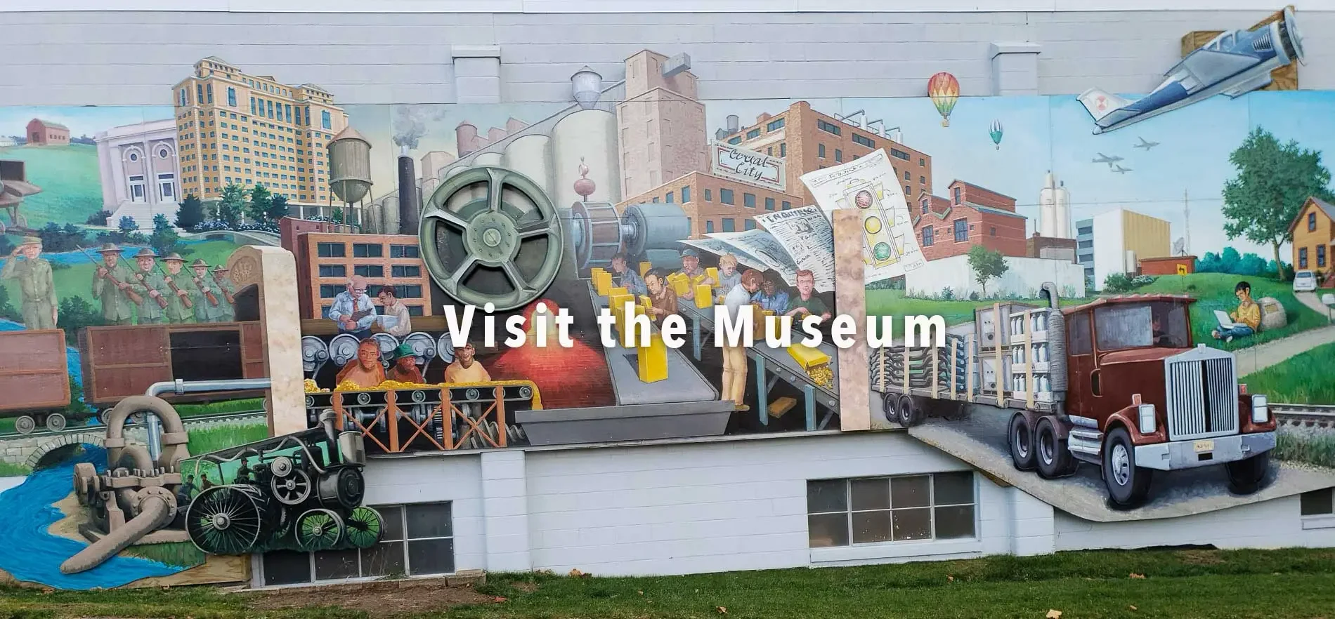 Colorful mural depicting historical and modern scenes, including factory buildings, soldiers, a train, a truck, a person using a laptop, hot air balloons, and the text "Visit the Museum".