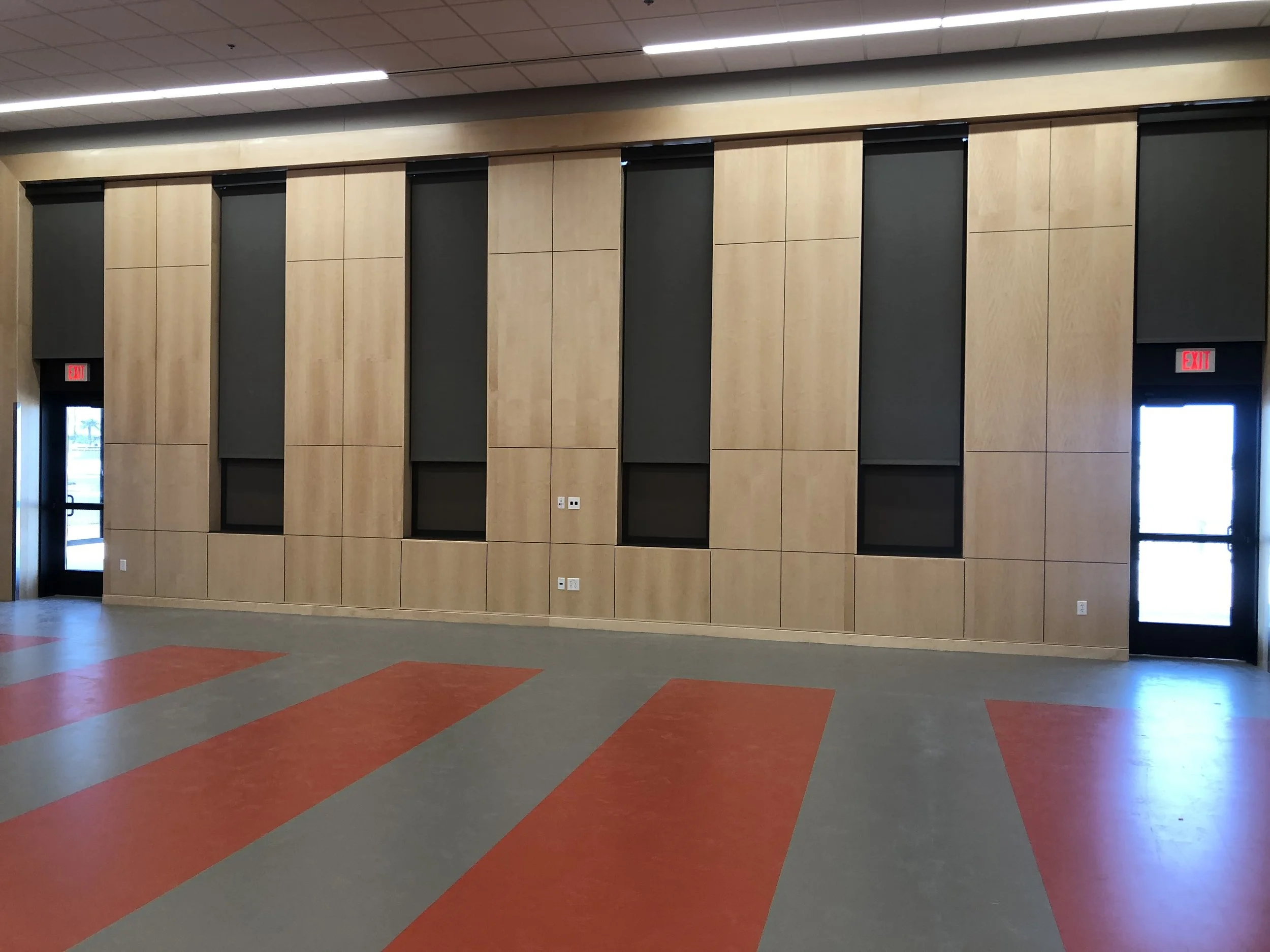 View of an interior space with a wood-paneled wall, black doorways, and a colorful patterned floor.