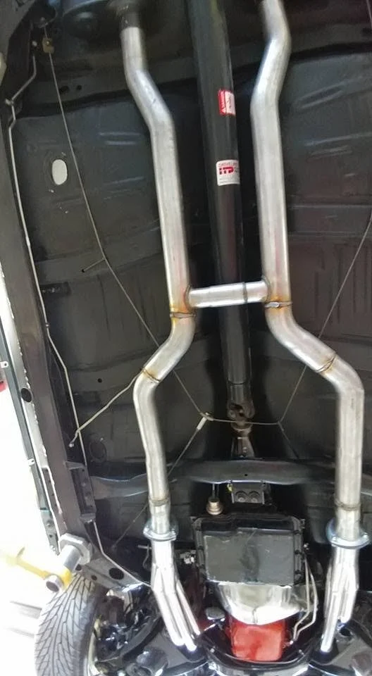 Underneath view of a vehicle's exhaust system with multiple pipes.