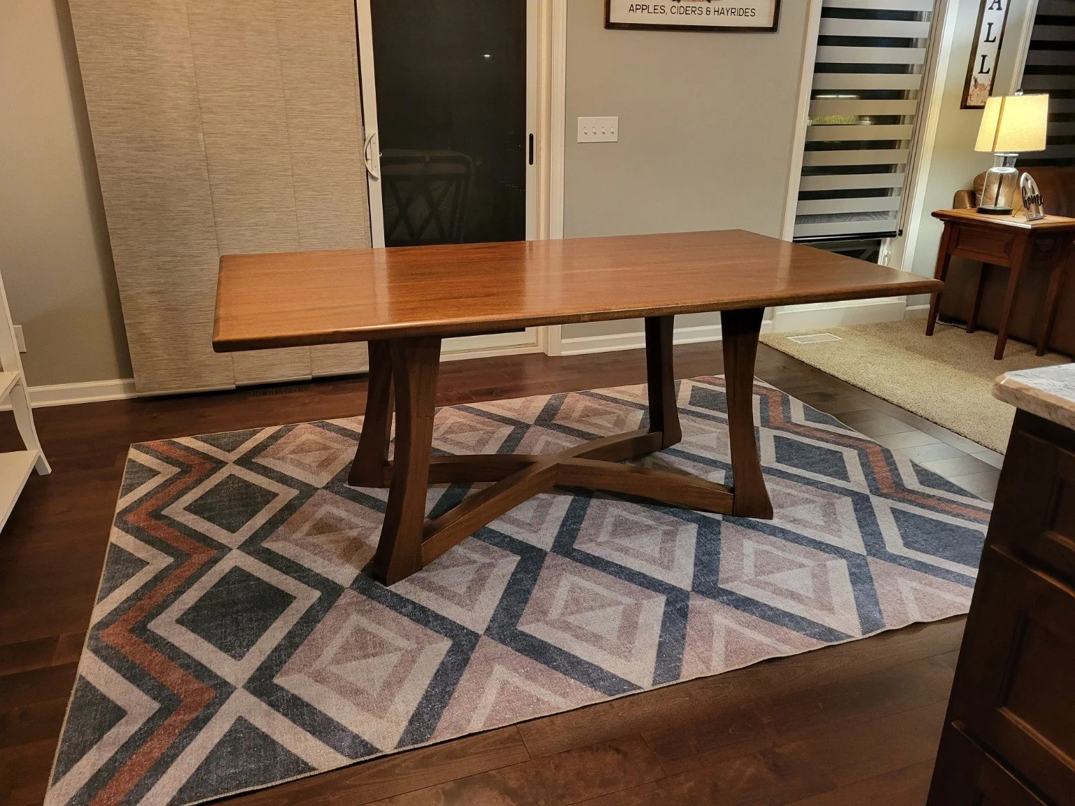 A wooden dining table on a patterned geometric area rug in a dining room.