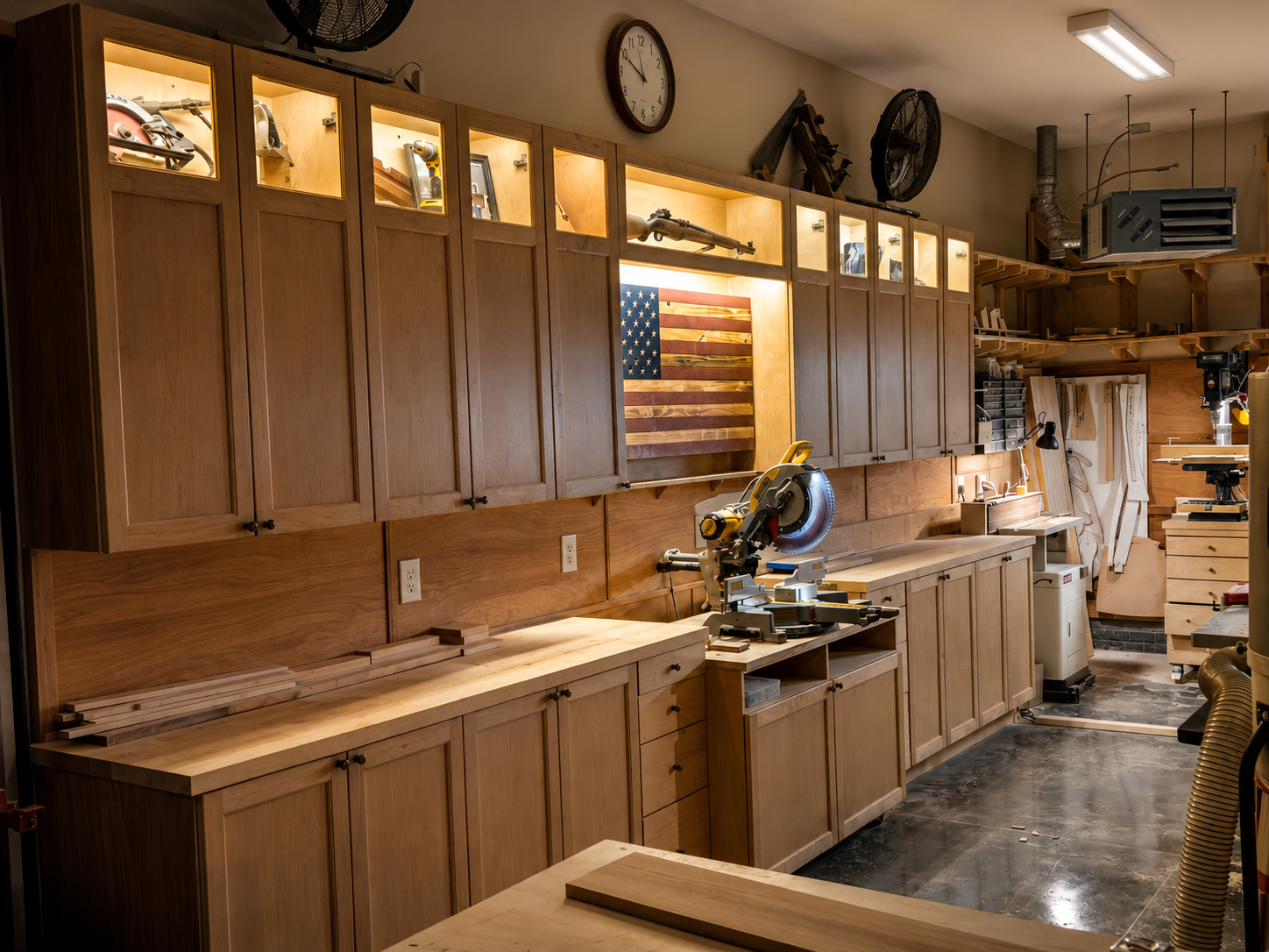 A woodworking shop with wooden cabinets, a miter saw, and woodworking tools. The shop has American flag art and a clock on the wall.